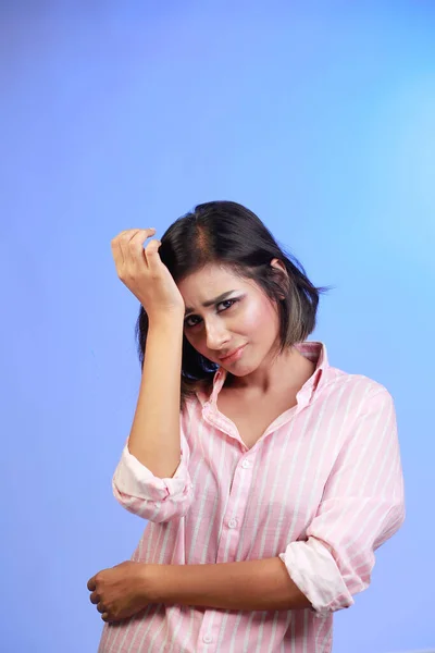 青いグラデーションの背景にピンクのシャツを着た若い美しい女性は 痛みや片頭痛のために頭痛 絶望的でストレスを受けています 手を頭に — ストック写真
