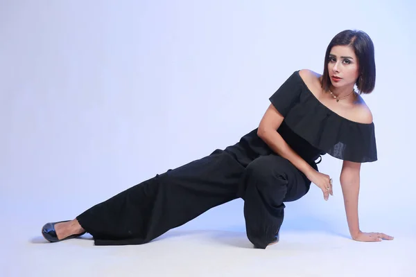 Fashion portfolio Portrait shot of a young, attractive, beautiful and stylish Pakistani woman in a Black jumpsuit. She is posing on a Studio background