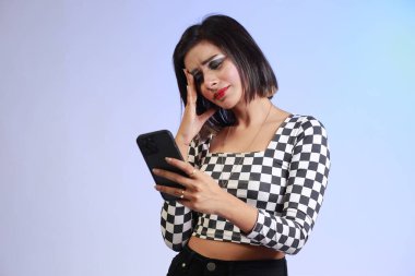 Young beautiful girl in a black and white shirt on a stressful phone call, expressive emotions and gestures of a tensed girl