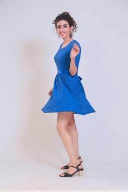 Girl in a blue dress, posing fashionably on a isolated studio background