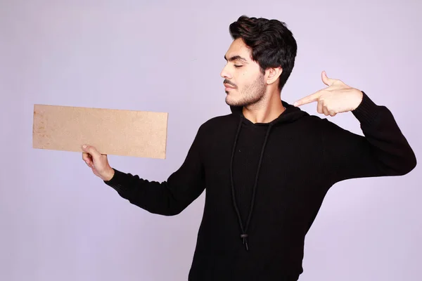 Young attractive asian male model, Holding an empty sign copy space, Pointing and looking at it. Handsome man presenting your brand or offer