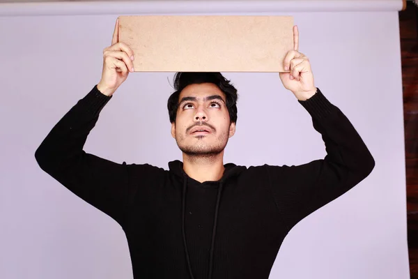 Young attractive asian male model, Holding an empty sign copy space and looking in Camera. Handsome man presenting your brand or offer