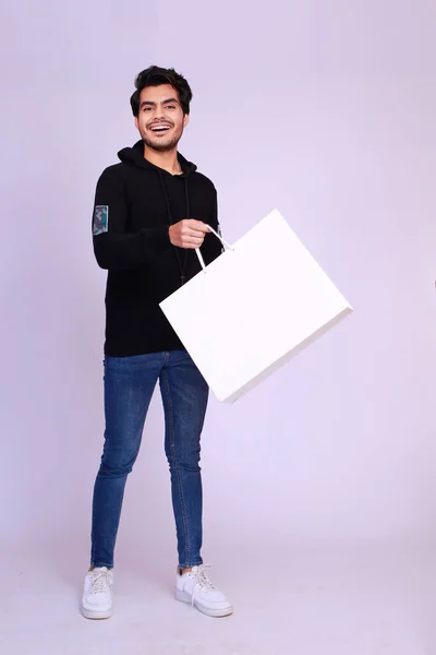 Young Excited Asian Male landed from a jump out of excitement holding a shopping bag, grabbing a shopping deal concept