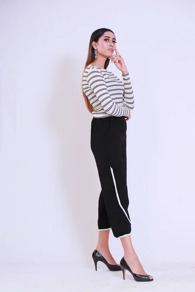 Young Attractive girl with curvy body wearing striped full sleeves shirt and black pyjamas, Posing fashion and glamour on a studio background wearing high heels