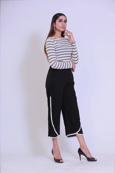 Young Attractive girl with curvy body wearing striped full sleeves shirt and black pyjamas, Posing fashion and glamour on a studio background wearing high heels