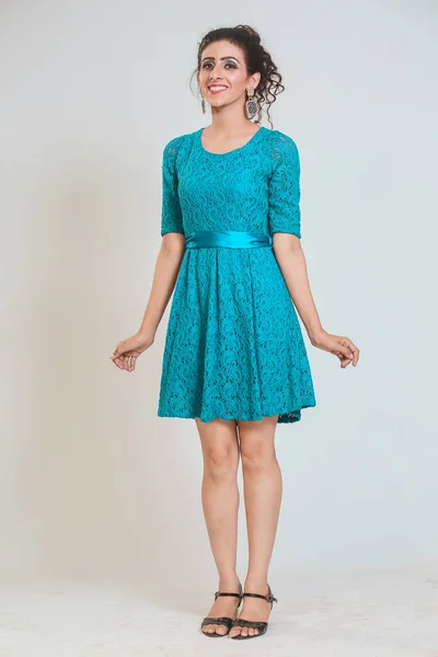 Girl in a turquoise dress, posing fashionably on a isolated studio background