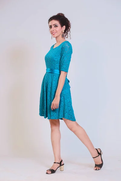 Girl in a turquoise dress, posing fashionably on a isolated studio background