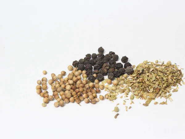 spilled black pepper, dried basil and coriander on a white background, fresh and aromatic cooking ingredients