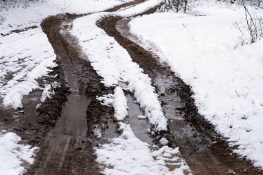 Çukurları ve su birikintileri olan eski bozuk bir yol.