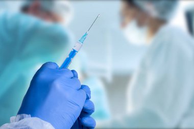 Close up man doctor holding syringe. Doctor in surgical mask and gloves preparing syringe for injection