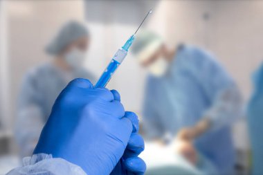 Close up man doctor holding syringe. Doctor in surgical mask and gloves preparing syringe for injection