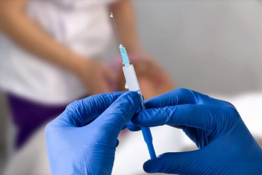 Close up man doctor holding syringe. Doctor in surgical mask and gloves preparing syringe for injection