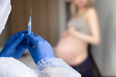 Hamilelik aşısı. Klinikte aşılanan hamile bir kadın. Doktor Corona Virüs Aşısı Enjeksiyonu Hastası 'na veriyor. Covid-19 Grip Koruması. Seçici odaklanma. Şırıngayı kapat.