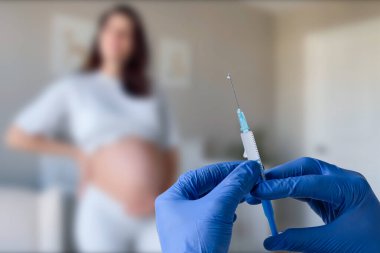 Hamilelik aşısı. Klinikte aşılanan hamile bir kadın. Doktor Corona Virüs Aşısı Enjeksiyonu Hastası 'na veriyor. Covid-19 Grip Koruması. Seçici odaklanma. Şırıngayı kapat.