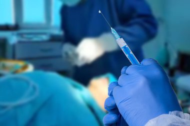 Close up man doctor holding syringe. Doctor in surgical mask and gloves preparing syringe for injection