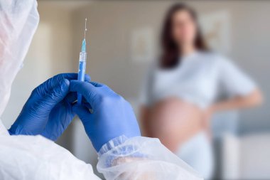 Hamilelik aşısı. Klinikte aşılanan hamile bir kadın. Doktor Corona Virüs Aşısı Enjeksiyonu Hastası 'na veriyor. Covid-19 Grip Koruması. Seçici odaklanma. Şırıngayı kapat.