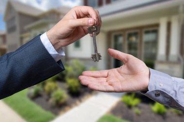 Başka bir ele anahtar veren bir el. Arka plandaki ev.