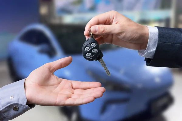 Auto business, car sale, transportation, people and ownership concept - close up of car salesman giving key to new owner or customer over auto show background