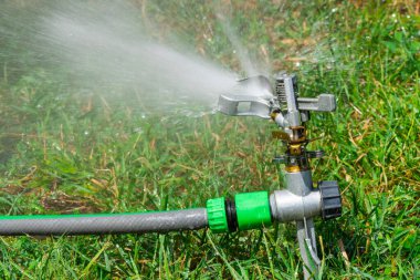 Otomatik fıskiye sistemi yeşil çimlerin arka planında çimenleri suluyor, yakın plan