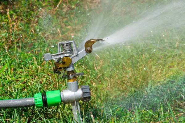 自动洒水系统在草坪上浇灌绿草的背景 — 图库照片