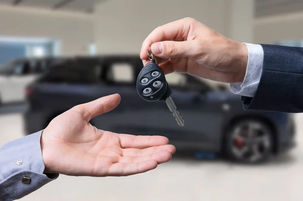 Close-up of dealer handing keys to new owners at a car show Automotive business Car sales Agreement Concept Men car salesman handing over new car keys