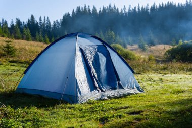 Dağın tepesinde kamp çadırı ve arka planda muhteşem bir gündoğumu. Temiz hava için zaman harcamak. Seyahat kavramı