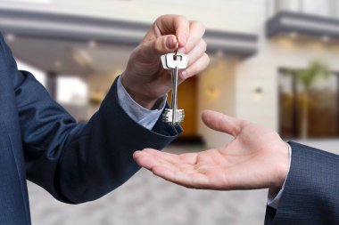 Başka bir ele anahtar veren bir el. Arka plandaki ev.