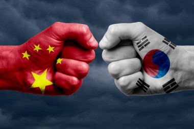 Çin, Kore 'ye karşı Güney Yüzleşmesi, Dini Çatışma. Çin ve Kore 'nin güneyinde boyanmış bayraklı erkek yumrukları. Koyu bulutlar