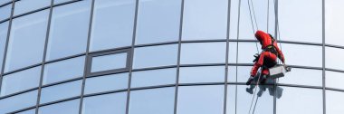 Modern bir binada cam temizliği yapan profesyonel bir işçi yeni ve parlak bir görünüş için el değmemiş cam yüzeyler sağlıyor..