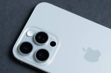 Elma iPhone 15 Pro Max, kutusuz ve siyah üzerine sergilenmiş, gelişmiş kamera sistemini vurguluyor.