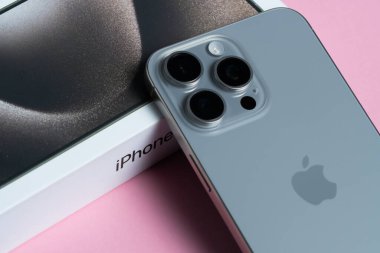 Gelişmiş kamera lensleriyle gösterişli iPhone 15 Pro Max minimalist pembe bir yüzeye yerleştirildi.