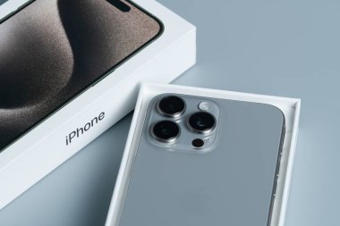 Apple iPhone 15 Pro Max, en son üç arka kameralı akıllı telefon modeli, yumuşak gri bir arkaplanda ayrıntılı olarak fotoğraflanmış..