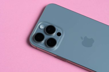 iPhone 15 Pro Max 'in yakın çekimi, temiz ve izole edilmiş pembe arka planda üç lensini gösteriyor.