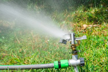 Otomatik fıskiye sistemi yeşil çimlerin arka planında çimenleri suluyor, yakın plan