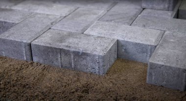 Kum tabanına bir dizi gri kaldırım taşı yerleştiriliyor. Bu da bir peyzaj projesinde yer alan titiz dizilimi ve hazırlığı gösteriyor..