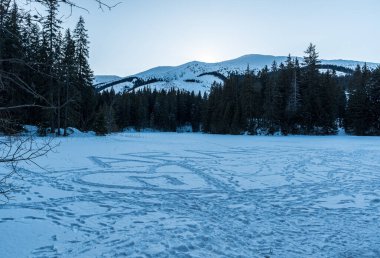 Frozen and snow covered Vrbicke pleso lake with hills above in winter Low Tatras mountains in Slovakia clipart