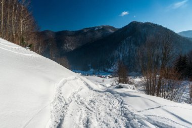 Tepelerle güzel bir kış günü, Vysna Revuca köyü, Slovakya 'da kar ve mavi gökyüzü