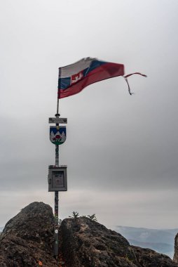 Rocky summit of Zubrid hill in Sulovske vrchy mountains in Slovakia with flag of Slovakia during cloudy autumn day clipart