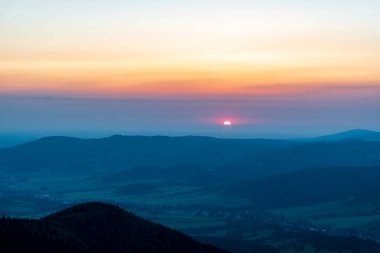 Sunrise with haze and colorful sky from Cwervena hora hill in Jeseniky mountains in Czech republic clipart