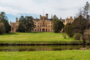 Lednice şatosu küçük nehri ve Çek Cumhuriyeti 'nde baharda ağaçlı çayırı olan
