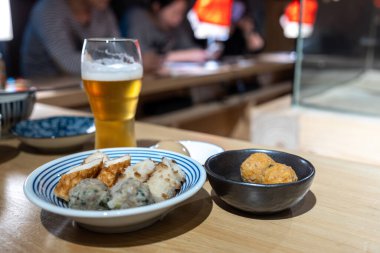 Japon köftesi ve balık köftesi tabakta bir bardak birayla..