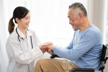 Tekerlekli sandalyedeki yaşlı adam ve onunla evde ilgilenen genç Asyalı bayan doktor. Tekerlekli sandalyedeki mutlu yaşlı adamı destekliyorum.