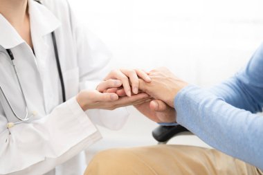 Kadın doktor eli, hastanede sandalyede oturan son sınıf erkek hastayla ilgileniyor ve konuşuyor. Sağlık hizmetleri kavramı.