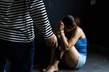 Silahlı soyguncu odadaki kadını tehdit ediyor. Saldırganlık suçu kavramı. Kadın ticareti ve insan kaçakçılığı kavramı. seçici odak.