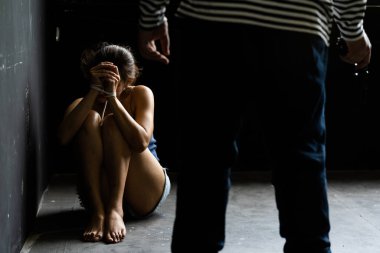 Kadın ticareti ve insan kaçakçılığı kavramı. Silahlı soyguncu odadaki kadını tehdit ediyor. Saldırganlık suçu kavramı. seçici odak.