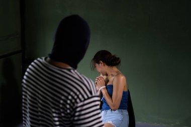 Kadın ticareti ve insan kaçakçılığı kavramı. Silahlı soyguncu odadaki kadını tehdit ediyor. Saldırganlık suçu kavramı. seçici odak.