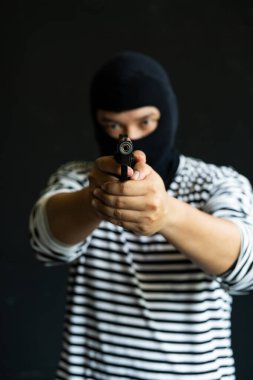 Silahlı maskeli bir soyguncu. Olgun bir adamla silahlı saldırı ve suç kavramı. Siyah üzerine silahlı soygun.. 