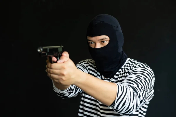 stock image Masked robber with gun. Concept of crime and fire arm assault with mature man. Armed robbery on black. 