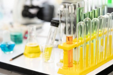 Farklı renkte sıvılarla dolu laboratuvar bardakları. Laboratuvar test tüplerinin renkli sıraları, bilim arka planı