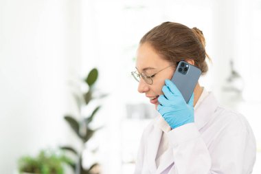 Kendine güveni tam bir kadın doktor ya da bilim adamı portresi, telefonda konuşan, konsültasyon yapan bir sağlık uzmanı. Bitki Laboratuvarı geçmişi.